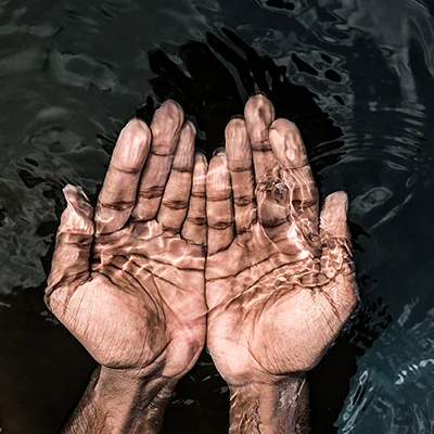 Clear water cupped in person's hands